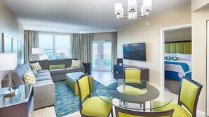 Une chambre d’hôtel moderne avec un canapé, une table à manger en verre et un téléviseur.