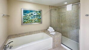 Une salle de bain moderne avec une grande baignoire, une douche à l’italienne et un tableau au mur.
