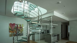 A modern interior with a spiral staircase, a kitchen area, and a dining space. - Dukley Penthouse 3 Bedrooms (Budva)