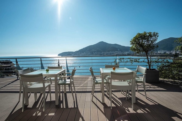 A deck with outdoor seating overlooking a coastal view.