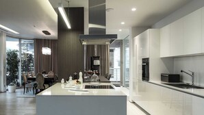 A modern kitchen with a central island, stainless steel appliances, and a dining area with a view. - Dukley Penthouse 3 Bedrooms (Budva)