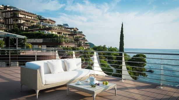 A balcony with a white sofa and a table set with a teapot, cups, and a pear. - Dukley Penthouse 3 Bedrooms (Budva)