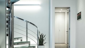 A modern interior with a spiral staircase, a potted plant, and a hallway leading to a door. - Dukley Penthouse 3 Bedrooms (Budva)