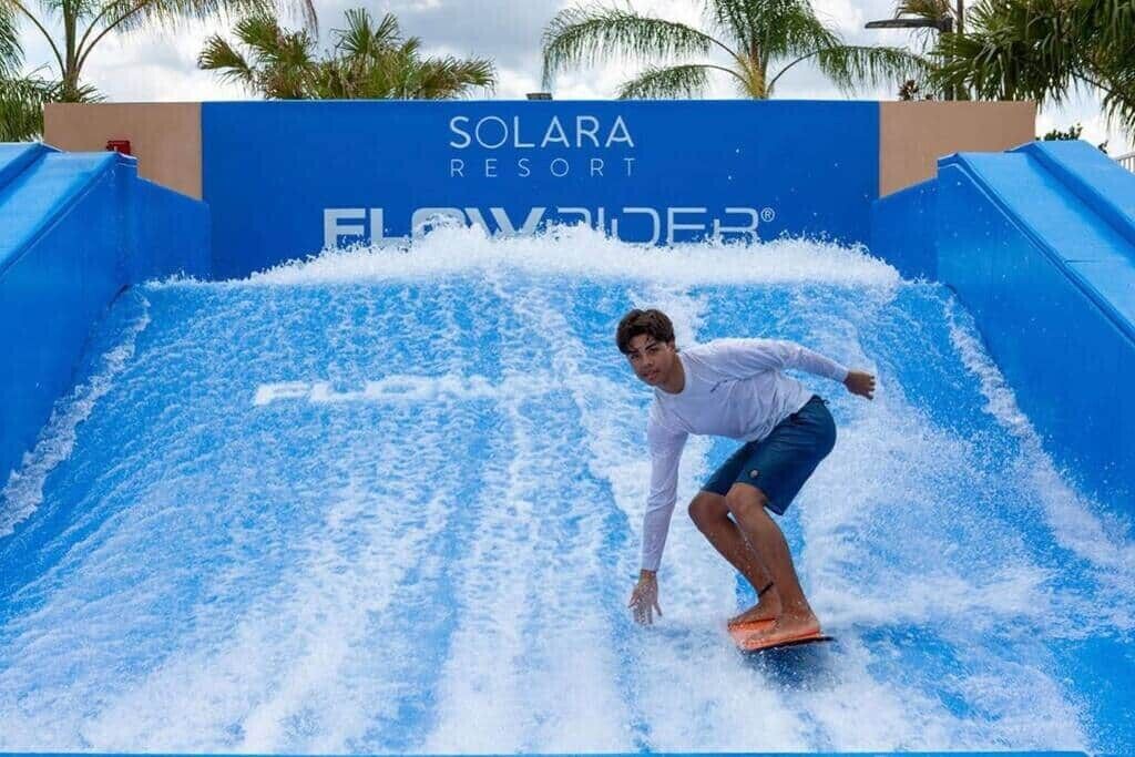 A man surfing on a wave in a water park at Solara Resort.