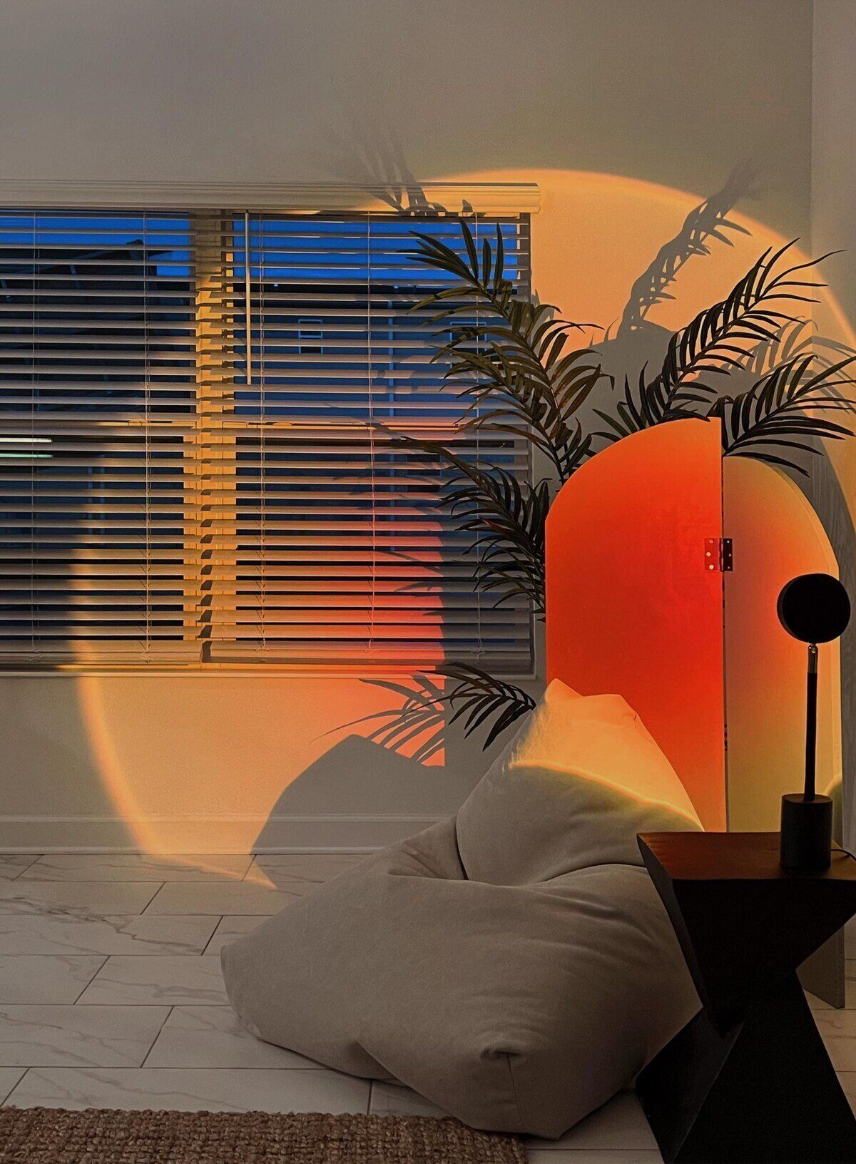 Un salon moderne avec une grande fenêtre, un canapé, une lampe et une plante.