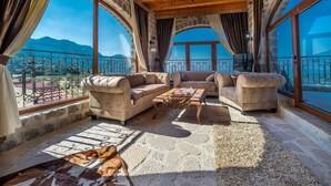 Un ampio balcone con pavimento in pietra, divani in pelle e soffitto in legno.