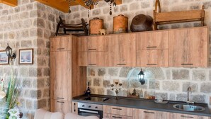 Una cucina rustica con mobili in legno, un muro in pietra e un lampadario.