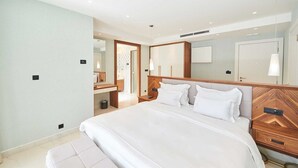 Une chambre d’hôtel moderne avec un grand lit, une tête de lit en bois et une table de chevet avec une lampe.