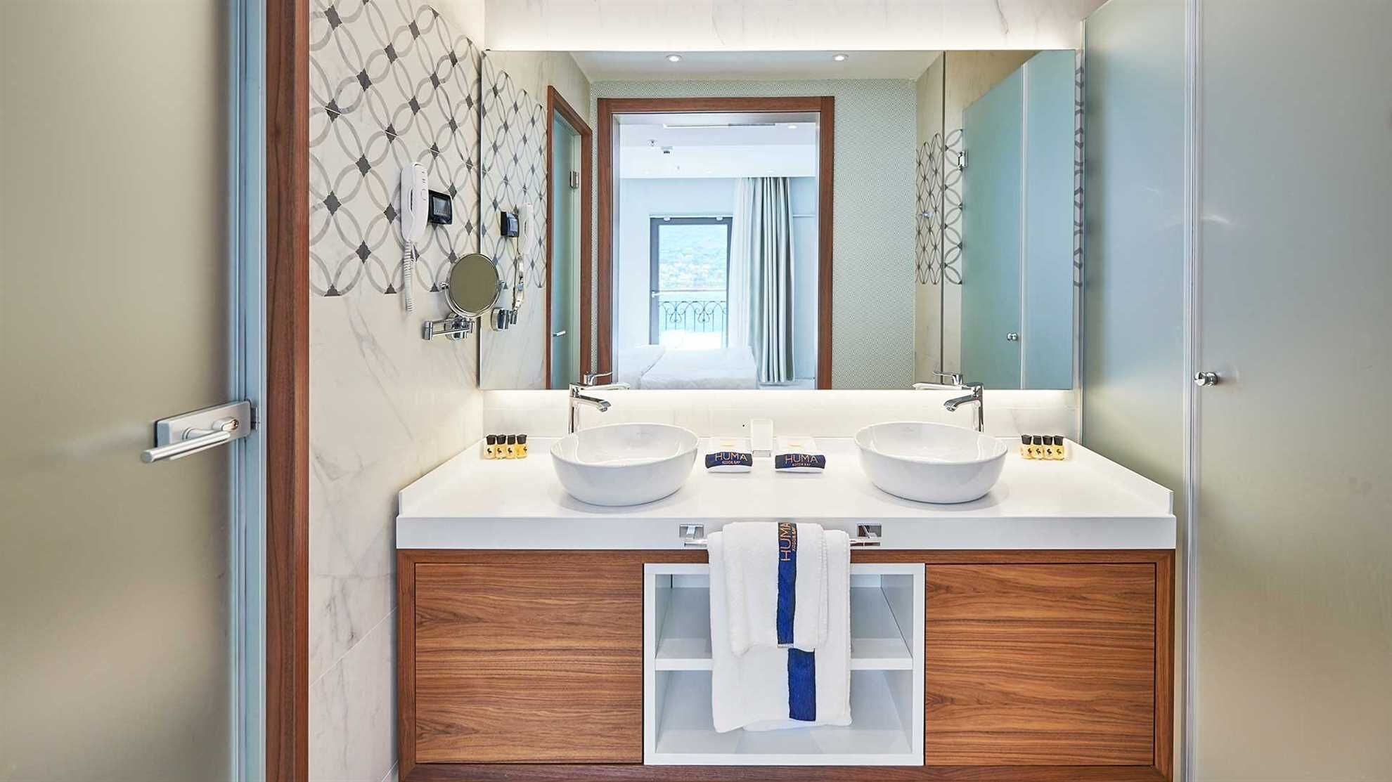A modern bathroom with two sinks, a mirror, and a towel rack.