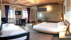 Una camera d'albergo con due letti, una scrivania, un televisore e un grande specchio.