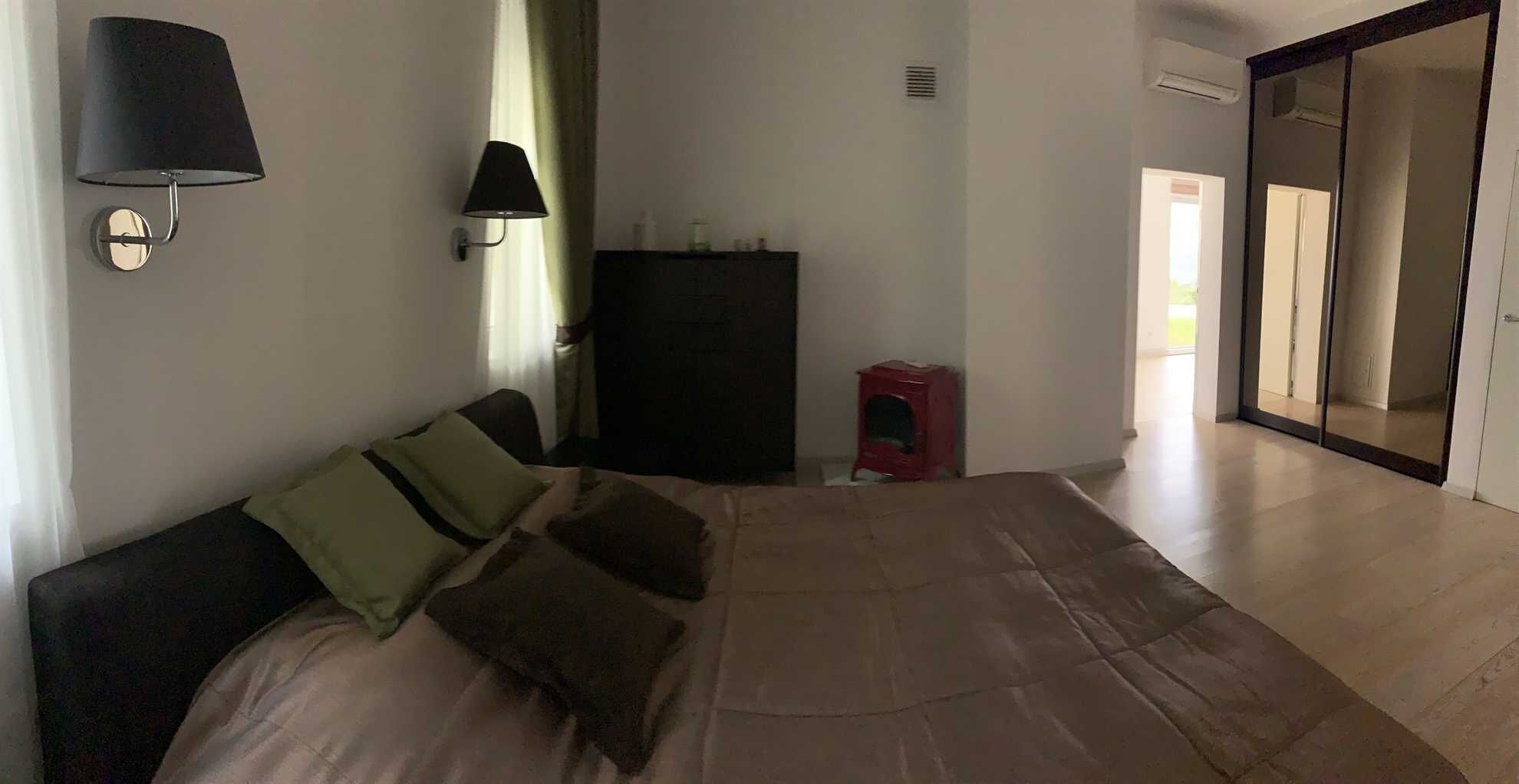 A bedroom with a bed, a nightstand, a lamp, and a wardrobe.