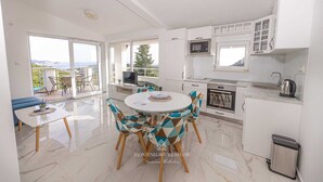 Une cuisine moderne avec des meubles blancs, un four à micro-ondes et un évier. On y trouve également un coin repas avec une table ronde et des chaises.