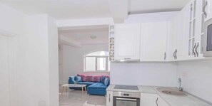 Eine moderne Küche mit weißen Schränken, einem eingebauten Backofen und einem Fenster über der Spüle.
