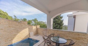 Eine Terrasse mit Schwimmbad, Tisch und Stühlen.