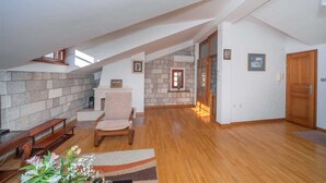 Un ampio loft con soffitto alto, parete in pietra, panche in legno, un camino e una porta in legno.