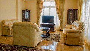 Uma sala de estar com dois sofás de couro, uma televisão e dois armários de madeira.