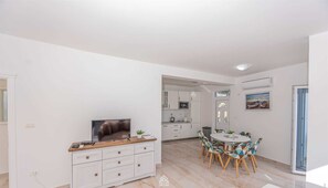 A modern living room with a TV, dining area, and kitchen.