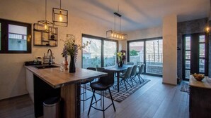 Una cocina moderna con una isla central, iluminación colgante y ventanas amplias.