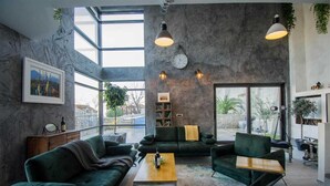Un salón amplio con un gran ventanal, un sofá verde, una mesa de centro y una estantería.