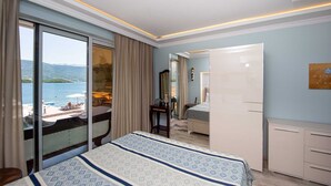 Camera d'albergo con un letto grande, una scrivania, una sedia, un armadio e vista sulla spiaggia e sul mare.