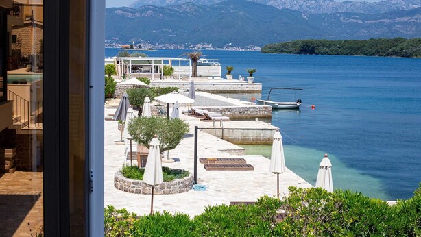Un hotel sul lungomare con posti a sedere all'aperto, piscina e vista sul mare e sulle montagne.