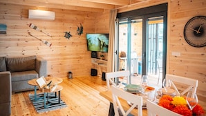 Interior acogedor de una cabaña de madera con sala de estar, comedor y televisor.