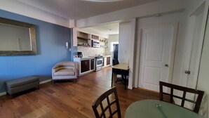 Una sala de estar moderna con una mesa de comedor y sillas, un sofá, y una cocina al fondo.