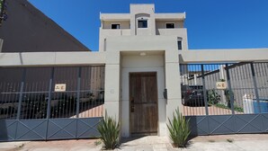Un edificio moderno con una entrada central, dos grandes puertas metálicas y un vehículo estacionado en el interior.