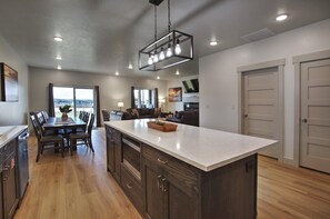 A modern kitchen with a large island, wooden cabinetry, and a dining area with a table and chairs.