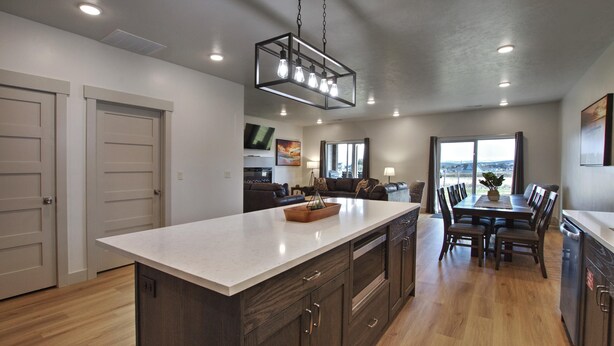 A modern kitchen with a large island, wooden cabinets, and a dining area with a table and chairs.