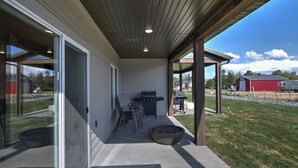 A covered patio with a grill, outdoor seating, and a fire pit.