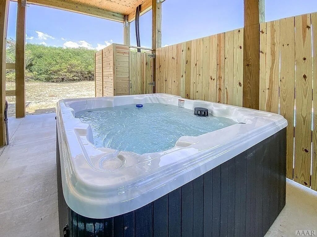 Un jacuzzi en un entorno exterior con valla de madera y una vista despejada del paisaje circundante.