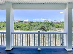 A covered outdoor area with a white railing, a view of houses and greenery in the background.