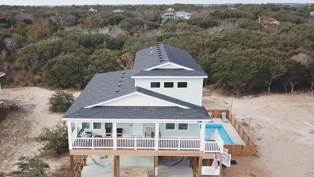 Uma casa de praia de dois andares com varanda e piscina.