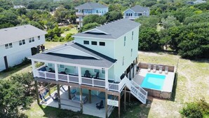 Uma casa de vários andares com varanda, piscina e área de deck.