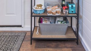 A kitchen with a white door, a shelf with kitchen utensils, a blue frying pan, and a toaster.