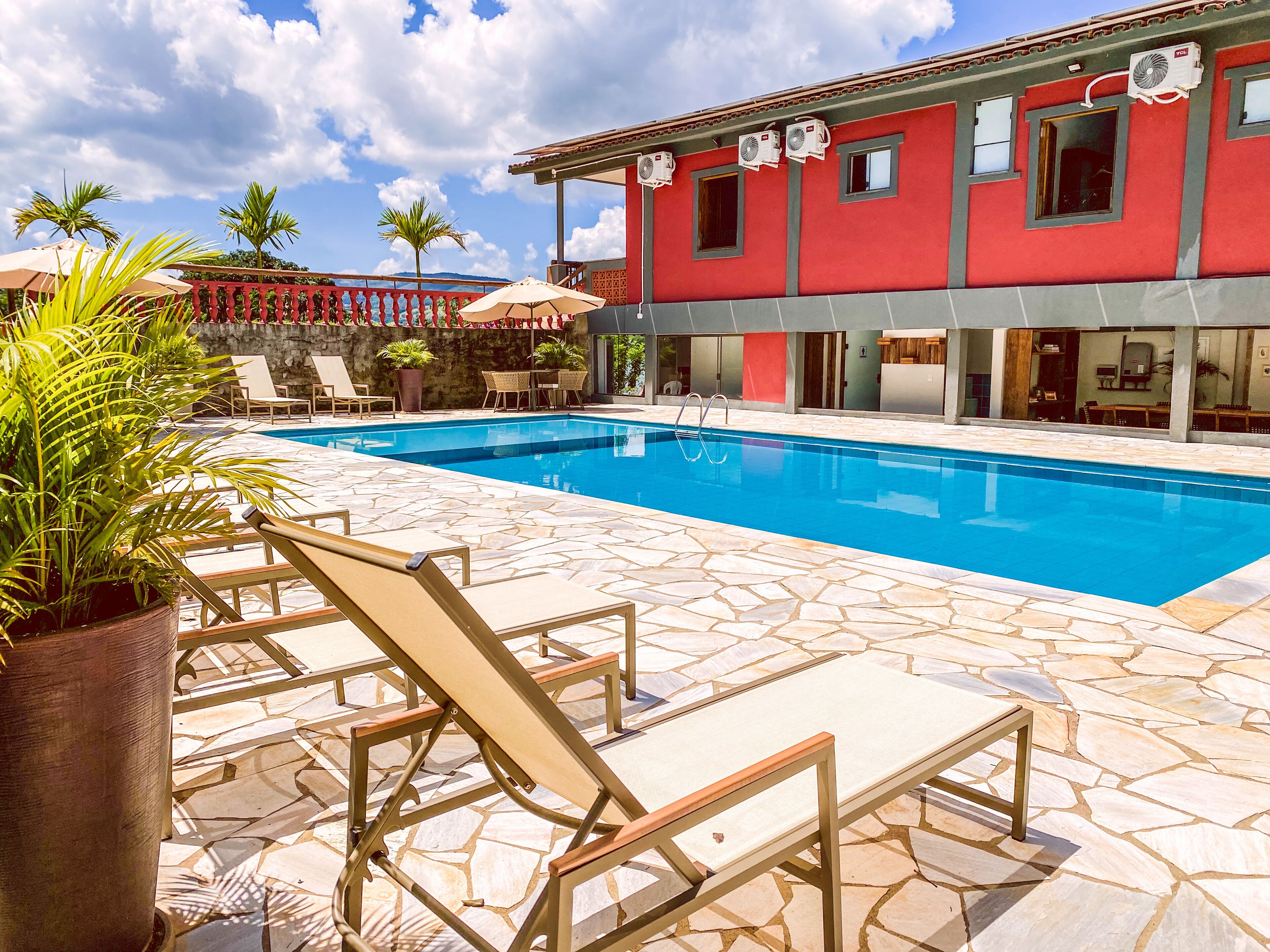 A swimming pool with lounge chairs and a red building in the background.