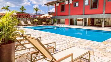A swimming pool with lounge chairs and a red building in the background.