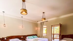 A hotel room with four single beds, each with a pillow and a rolled towel. There are hanging light fixtures above the beds. - Bica D'água Boutique Hotel (Capitólio)