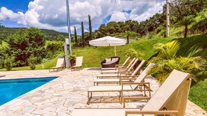 A poolside area with lounge chairs and a white umbrella. - Bica D'água Boutique Hotel (Capitólio)