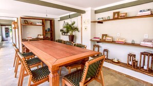 A spacious dining area with a long wooden table and matching chairs, surrounded by shelves with books and decorative items. - Bica D'água Boutique Hotel (Capitólio)