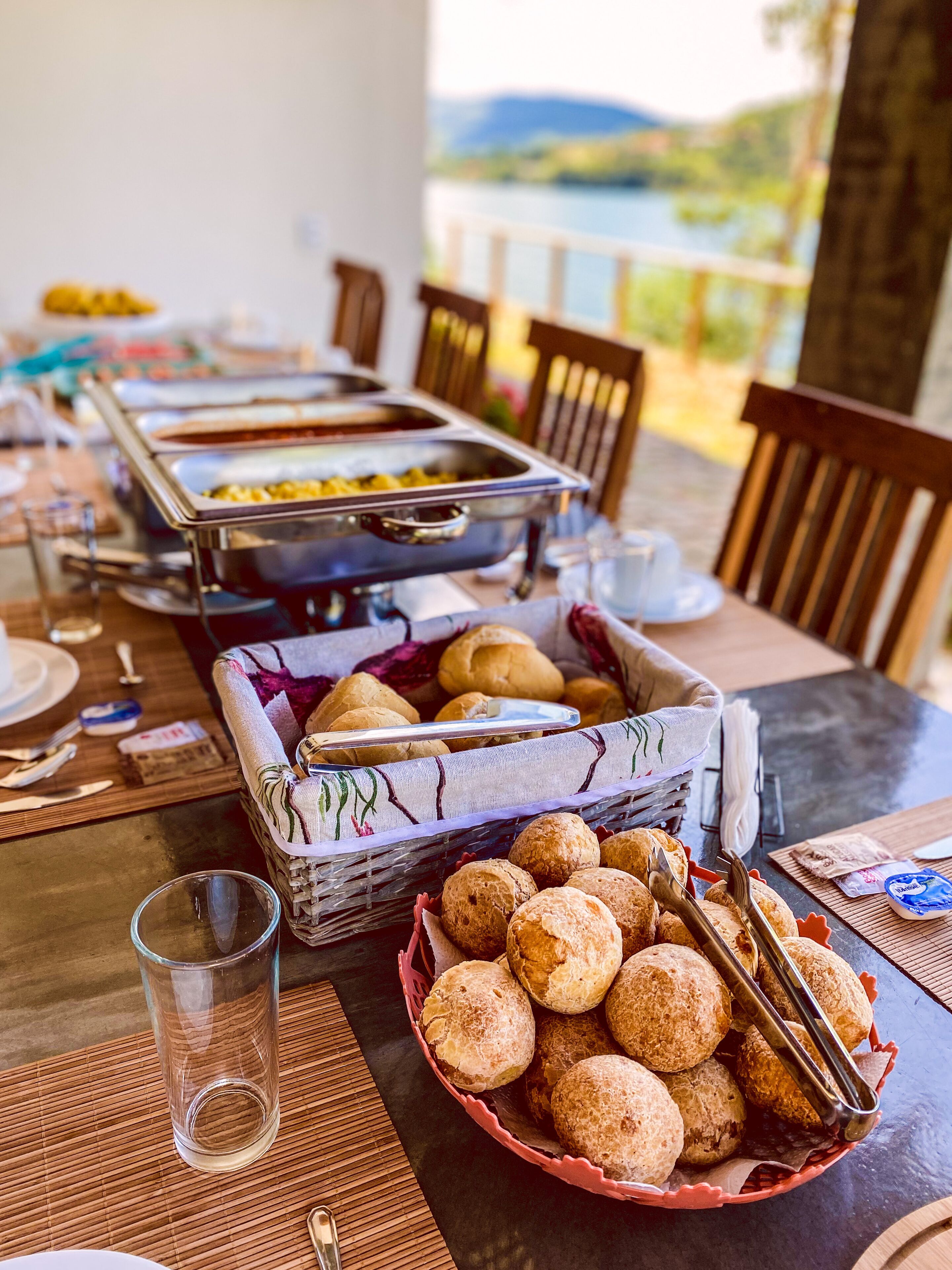 A buffet table with various food items, including a basket of bread rolls, a buffet station with multiple dishes, and dining utensils.