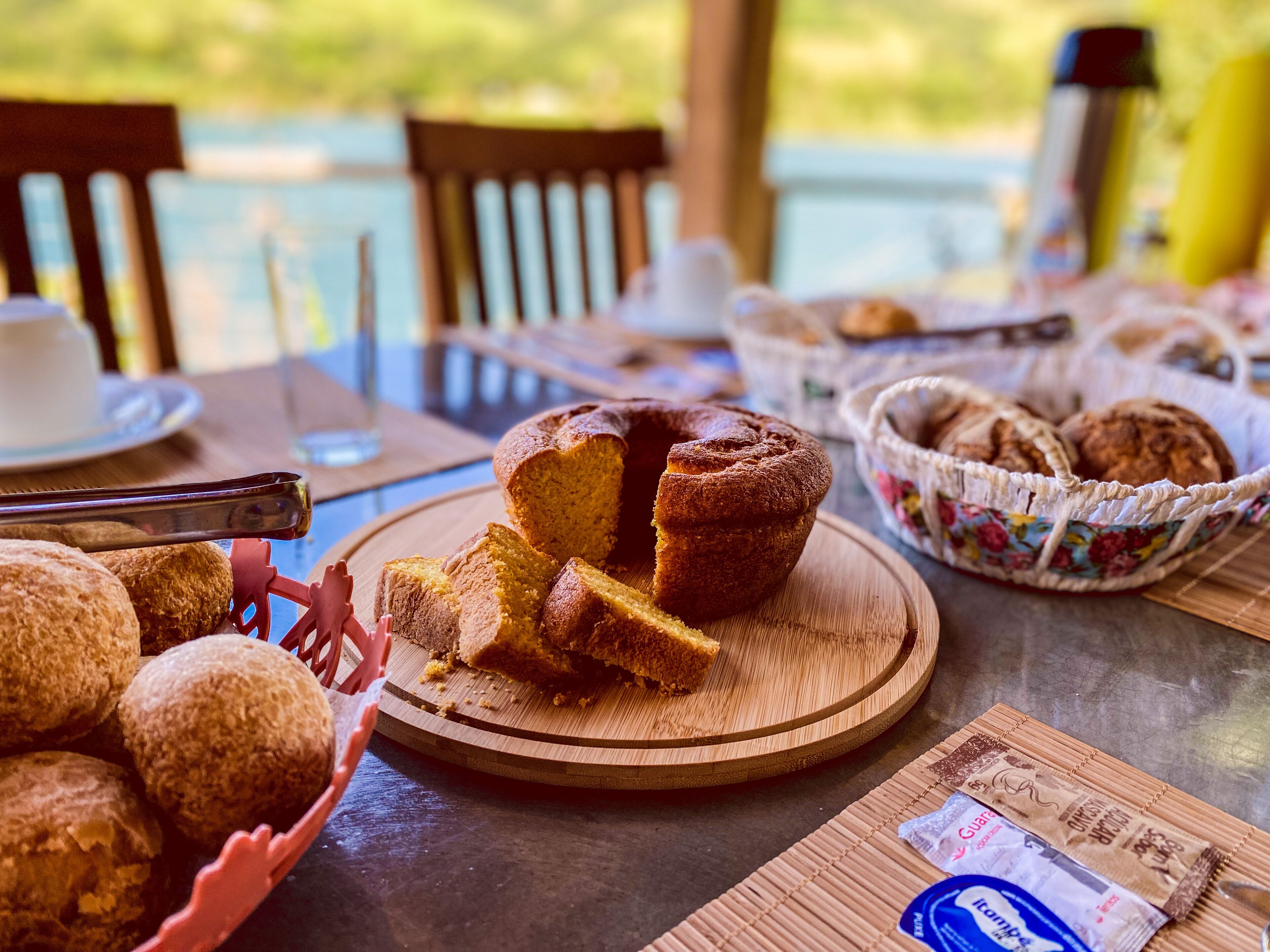 A table with a cake, bread, and a basket of pastries.