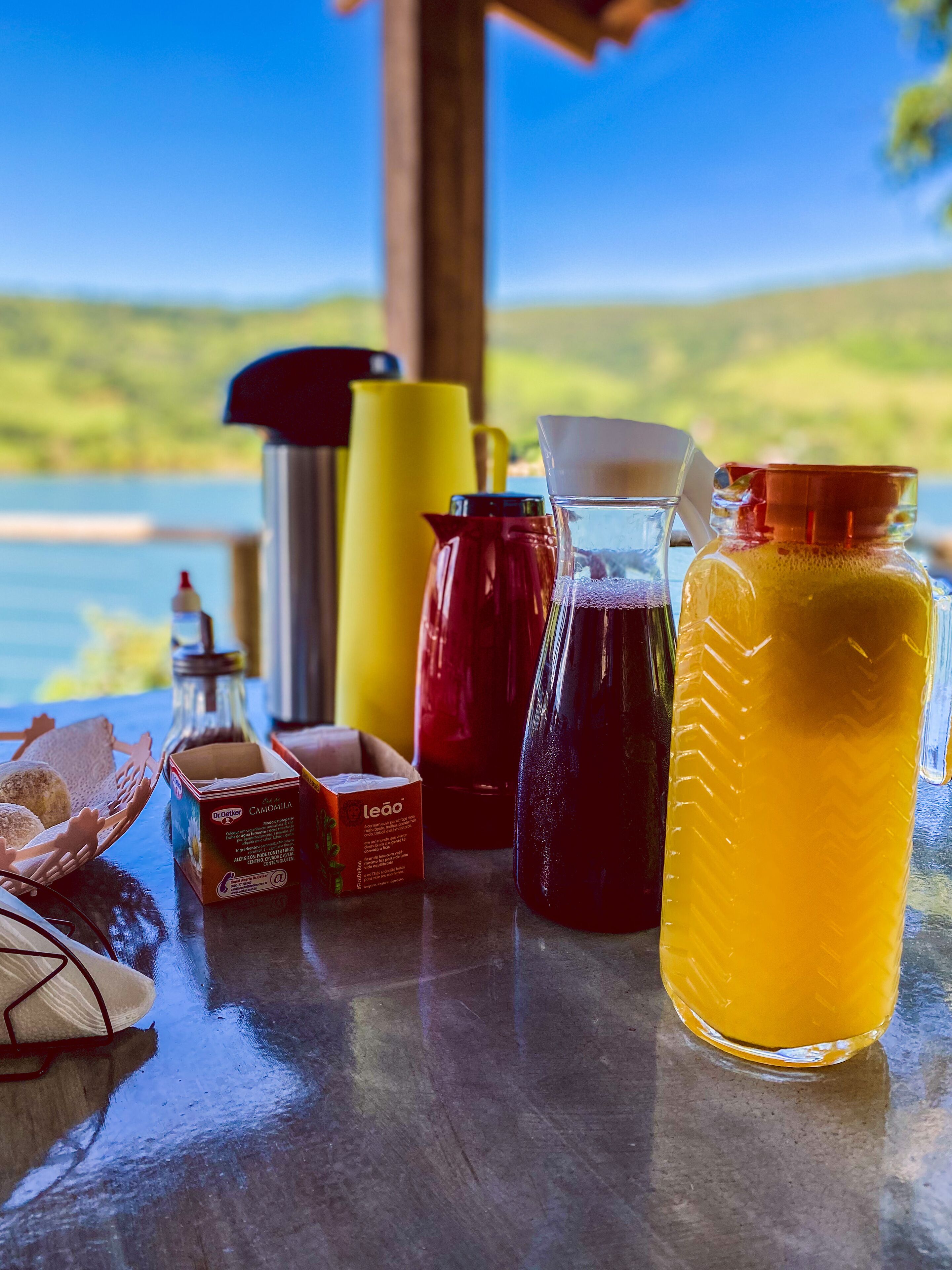 A table with various containers and a box of Leão brand products, set against a scenic outdoor backdrop.