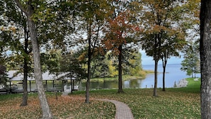 Un camí pavimentat que condueix a una zona de vaixells, envoltat d'arbres i un llac.