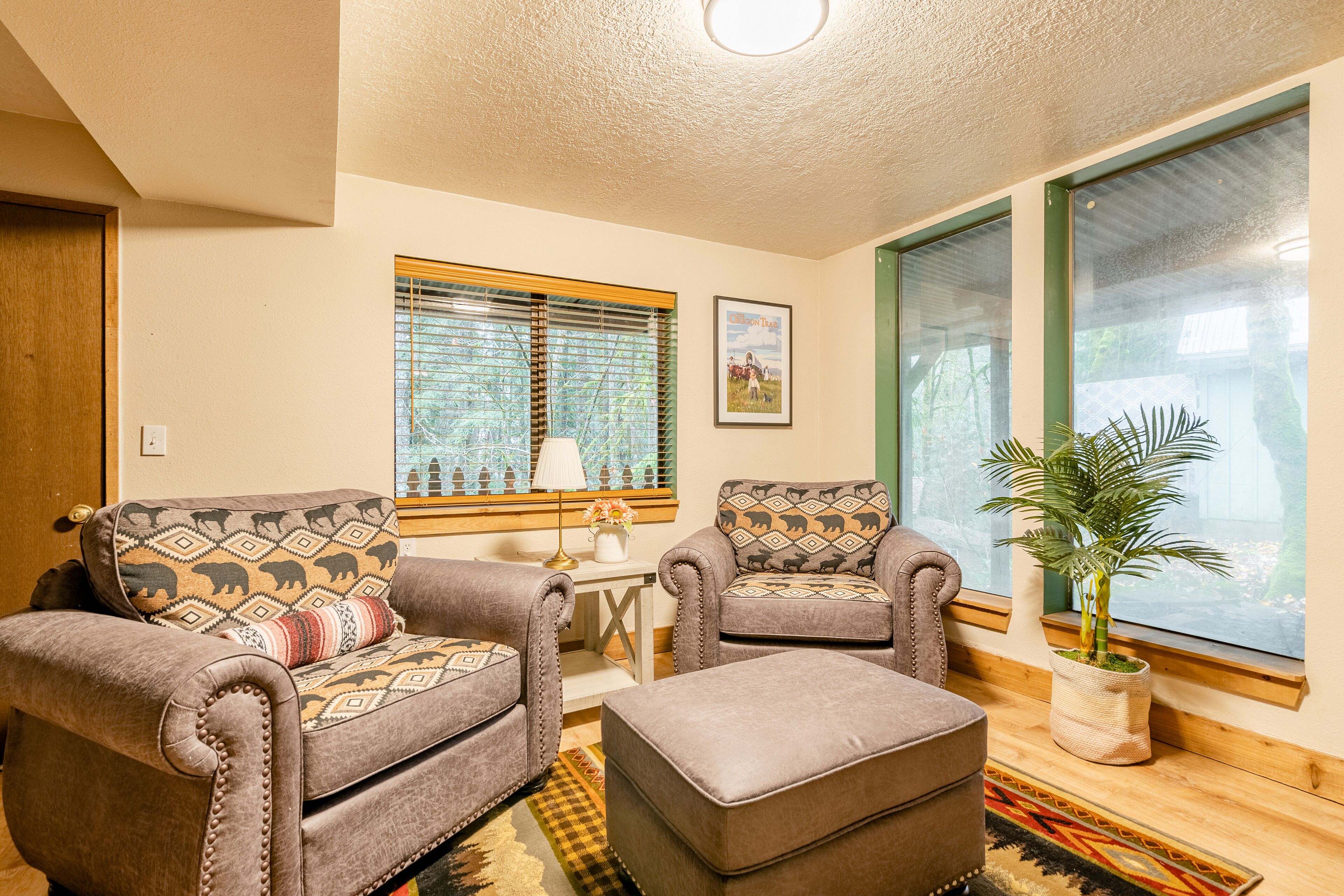 A cozy living room with two armchairs, a small table, and a potted plant.