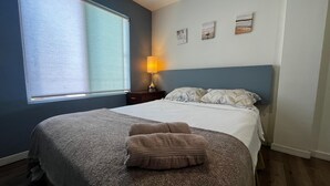 A neatly made bed with a grey blanket and two pillows, a bedside lamp, and three wall art pieces. - Spacious 2 bedroom apartment by the bullring (Tijuana)