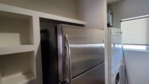 A compact kitchen with a stainless steel refrigerator, a built-in oven, and a washing machine. - Spacious 2 bedroom apartment by the bullring (Tijuana)