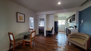 A spacious living area with a wooden floor, a dining table with chairs, a sofa, and a kitchen area with cabinets and a microwave. - Spacious 2 bedroom apartment by the bullring (Tijuana)