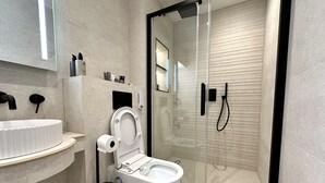 Een moderne badkamer met toilet, wastafel en douche.